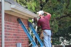 Male,Contractor,Installing,A,Gutter,System,On,A,Two-story,Residential